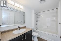 Bathroom featuring a vanity with a light-toned countertop, undermount sink, and dark cabinetry - 