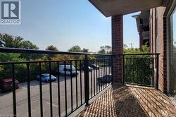 Private balcony featuring wood-finish floor tiles, black metal railings, and a brick exterior wall - 