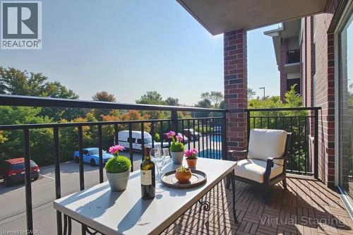 Private balcony featuring wood-finish tile flooring and a black metal railing - 41 Goodwin Drive Unit# 202, Guelph, ON 