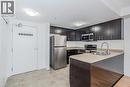 Modern kitchen featuring stainless steel appliances, dark wood-finish cabinetry, a light-toned countertop, and a white tile backsplash - 41 Goodwin Drive Unit# 202, Guelph, ON 