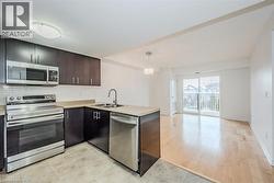 Kitchen featuring dark wood-finish cabinetry, stainless steel appliances, a double basin sink, and tile flooring - 