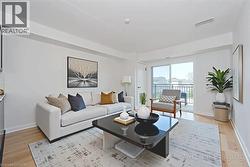 Living area featuring light wood-finish flooring, white painted walls, and a sliding glass door opening to a balcony with black metal railings - 