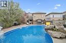 Expansive backyard featuring an inground swimming pool, surrounding concrete patio, and a rock waterfall feature - 44 Mcnichol Drive, Cambridge, ON  - Outdoor With In Ground Pool With Backyard 