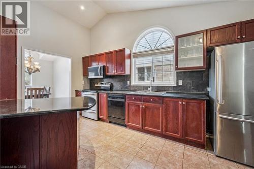 Kitchen featuring vaulted ceilings, cherry wood cabinetry, stainless steel appliances, stone countertops, and tile flooring - 44 Mcnichol Drive, Cambridge, ON - Indoor Photo Showing Kitchen
