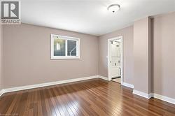 Hardwood flooring throughout, complemented by a single window with blinds - 