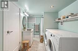 *VIRTUALLY STAGED* Combined laundry and bath with a white vanity, oval mirror, wall-mounted lighting, and a window with blinds - 