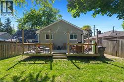 Expansive backyard featuring a wood deck with steps, a concrete patio, and a manicured lawn - 