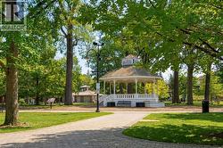 White gazebo with a multi-tiered roof, ornate railings, and a foundational base - 