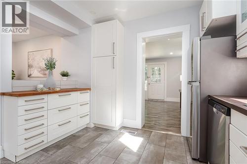 Contemporary kitchen featuring wood-finish countertops, subway tile backsplash, and light gray rectangular floor tiles - 40 Woodland Avenue, Kitchener, ON 