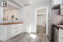 Contemporary kitchen featuring wood-finish countertops, subway tile backsplash, and light gray rectangular floor tiles - 