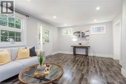 Bright living area featuring wood-finish flooring, recessed lighting, and white baseboards - 