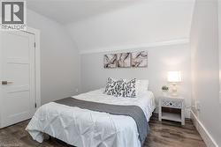 Room featuring wood-finish flooring, a three-panel interior door with brushed nickel hardware, and neutral wall tones - 