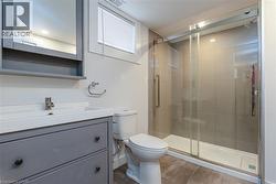 Contemporary bathroom featuring a spacious glass-enclosed shower with tiled walls and a white base, a gray vanity with an integrated white sink, a chrome faucet, and a wall-mounted medicine cabinet wi - 