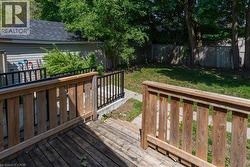 Expansive backyard featuring a wood deck, concrete pathway, and mature trees - 
