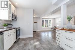 Contemporary kitchen featuring white cabinetry, stainless steel appliances, dark countertops, and a white subway tile backsplash - 