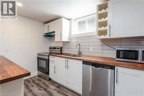 Kitchen featuring wood-finish countertops, white shaker-style cabinetry, and stainless steel appliances including a range, dishwasher, and microwave - 40 Woodland Avenue, Kitchener, ON 