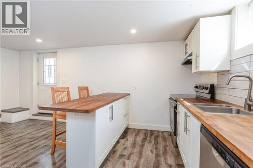 Kitchenette featuring wood-finish flooring, white cabinetry, butcher block countertops, stainless steel appliances, and a white subway tile backsplash - 40 Woodland Avenue, Kitchener, ON 