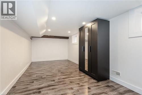 Spacious room featuring wood-finish flooring, recessed lighting, and a dark-toned built-in wardrobe with mirrored panels - 40 Woodland Avenue, Kitchener, ON 