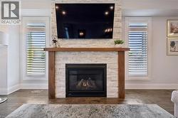 Stone veneer fireplace with wood-finish mantel and integrated gas insert - 