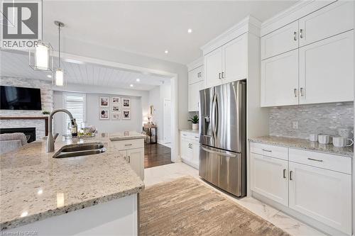 Kitchen featuring white cabinetry, stainless steel appliances, speckled countertops, and a tile backsplash - 72 Elmbank Trail, Kitchener, ON 
