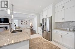 Kitchen featuring white cabinetry, stainless steel appliances, speckled countertops, and a tile backsplash - 