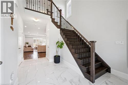 Entry foyer featuring marble-look tile flooring and a dark wood staircase with wrought iron balusters - 72 Elmbank Trail, Kitchener, ON 