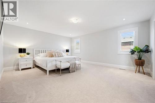 Expansive bedroom featuring light-colored carpeting, two windows with white plantation shutters, and a ceiling light fixture - 72 Elmbank Trail, Kitchener, ON 