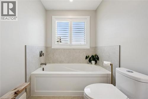 Alcove bathtub with light gray tiled surround and dark hardware - 72 Elmbank Trail, Kitchener, ON 