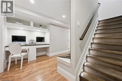 Wood-finish flooring throughout a dedicated workspace with built-in shelving, recessed lighting, and white baseboards - 72 Elmbank Trail, Kitchener, ON 