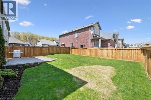 Expansive backyard featuring a lush lawn, wood privacy fencing, and a concrete patio - 72 Elmbank Trail, Kitchener, ON 