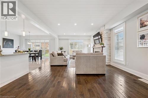 Open-concept living area featuring rich wood-finish flooring, a stone-clad fireplace, and white shiplap ceiling - 72 Elmbank Trail, Kitchener, ON 
