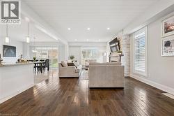 Open-concept living area featuring rich wood-finish flooring, a stone-clad fireplace, and white shiplap ceiling - 