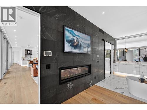 A dramatic real stone feature wall supplied by K2 Stone in Kelowna serves as a major architectural focal point within the suite as you enjoy the two-sided 5.5' linear fireplace. - 5835 Vicary Road, Peachland, BC 