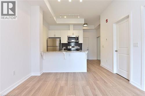 Open-concept living area featuring light wood-finish flooring, white walls, and recessed lighting - 4040 Upper Middle Road Unit# 105, Burlington, ON 