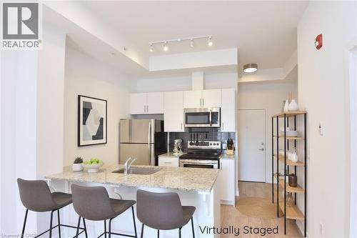 Kitchen featuring a peninsula with a built-in sink, light-toned countertop, and white cabinetry - 4040 Upper Middle Road Unit# 105, Burlington, ON 