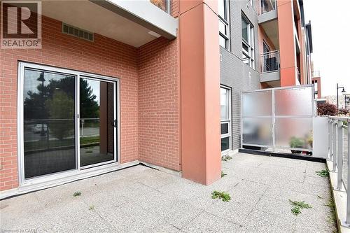 Ground-level patio featuring a sliding glass door entry, brick exterior, and a frosted privacy screen - 4040 Upper Middle Road Unit# 105, Burlington, ON 