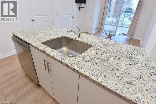 Kitchen island featuring a stainless steel undermount sink, a chrome faucet, and integrated stainless steel dishwasher - 4040 Upper Middle Road Unit# 105, Burlington, ON 