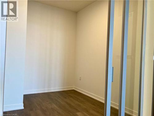 Interior room featuring wood-finish flooring, white baseboards, and a sliding glass door with a metal frame - 4878 Powers Common Unit# C-1105, Burlington, ON 