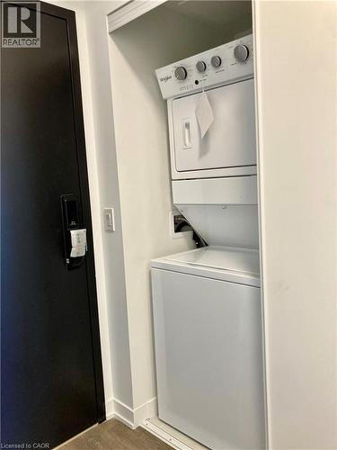 Integrated stacked laundry center with white appliances and utility shelving - 4878 Powers Common Unit# C-1105, Burlington, ON 