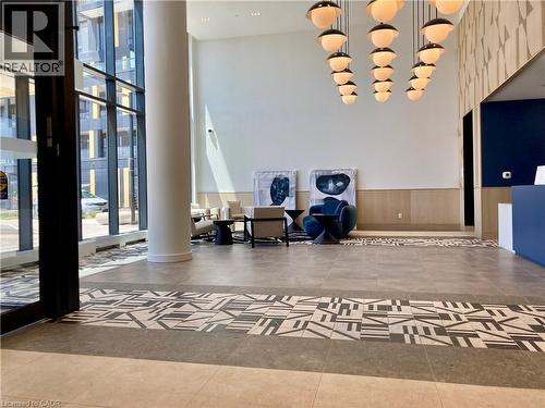 Spacious lobby featuring high ceilings, a contemporary chandelier, geometric accent wall, and large format floor tiles with a decorative inlay - 4878 Powers Common Unit# C-1105, Burlington, ON 