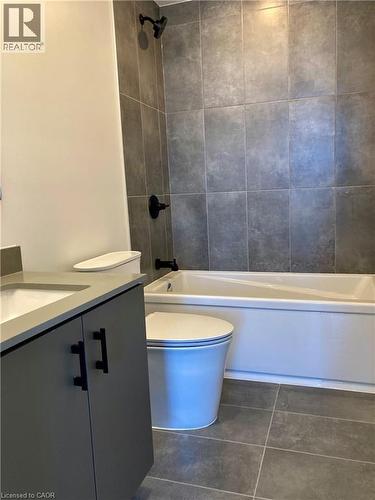 Bathroom featuring dark grey floor tiles and complementing wall tiles in the shower enclosure - 4878 Powers Common Unit# C-1105, Burlington, ON 