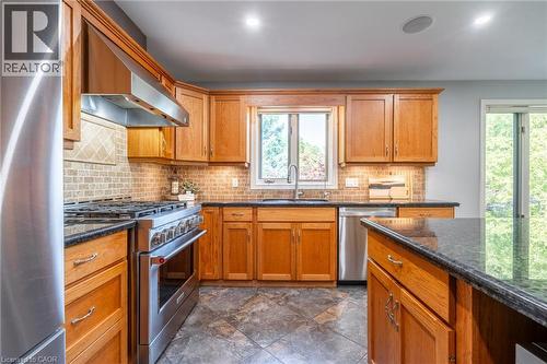 Kitchen with brown cabinets, stainless steel appliances, tasteful backsplash, a sink, and extractor fan - 18 Westie Road, Brantford, ON 
