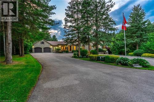 View of front of house featuring stone siding, an attached garage, aphalt driveway, and a front yard - 18 Westie Road, Brantford, ON 