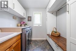 Laundry room with baseboards, washing machine and dryer, cabinet space, and stone finish flooring - 