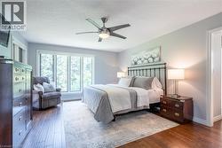 Bedroom featuring a ceiling fan, dark wood-style floors, baseboards, and a textured ceiling - 