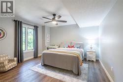Bedroom featuring baseboards, a textured ceiling, visible vents, a ceiling fan, and wood finished floors - 