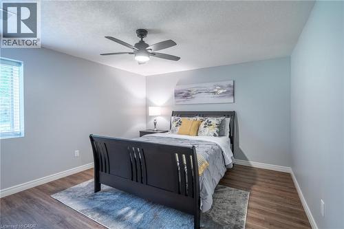 Bedroom with a textured ceiling, visible vents, baseboards, wood finished floors, and a ceiling fan - 18 Westie Road, Brantford, ON 