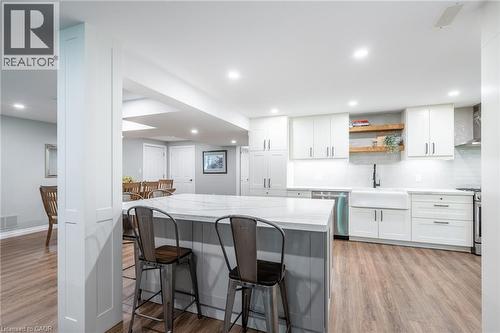 Kitchen featuring a kitchen bar, stainless steel appliances, white cabinetry, a sink, and wall chimney range hood - 18 Westie Road, Brantford, ON 