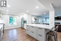 Kitchen with a breakfast bar area, light wood-style flooring, stainless steel appliances, and light stone countertops - 