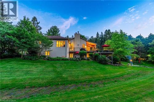 Rear view of property featuring stucco siding, a chimney, a lawn, and a deck - 18 Westie Road, Brantford, ON 
